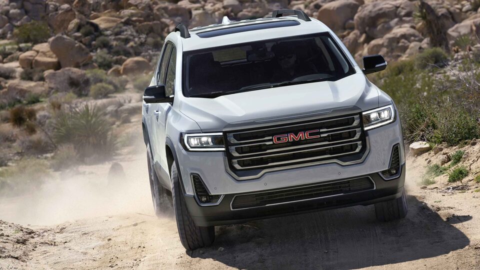 The Summit White GMC Acadia Driving Head-On Off-Road Kicking Up Dust
