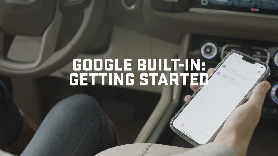 Man Holding Phone in a GMC Yukon With Text displaying Google Built-In: Getting Started