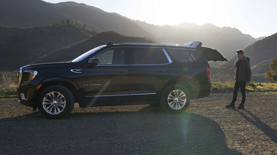 Man Opning 2022 GMC Yukon SLT Full-Size SUV's Trunk