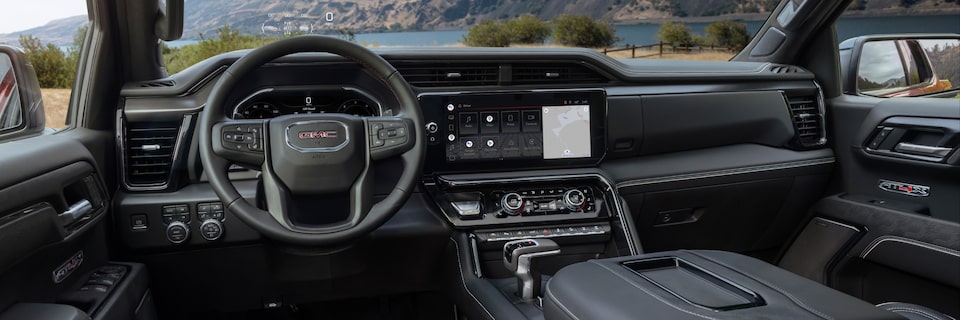 Steering Wheel, Dashboard, and Infotainment System on the GMC Sierra Parked Off-Road with Water and Mountains