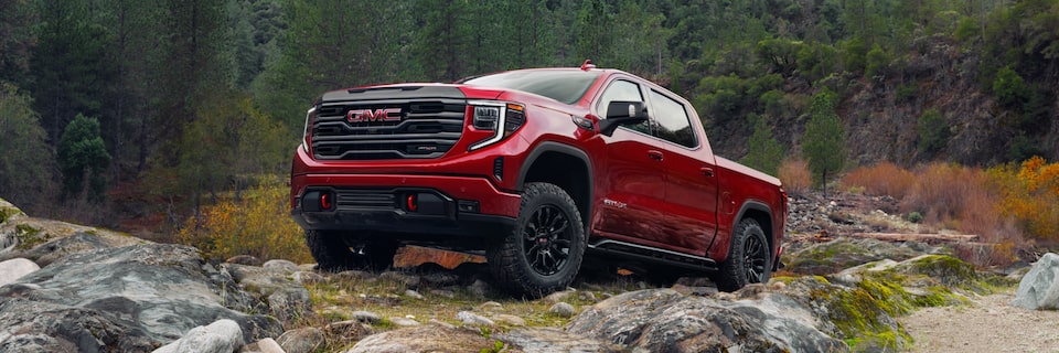 Cardinal Red GMC Sierra Pickup Trucked Parked Off-Road On Rocks With Trees and Hills