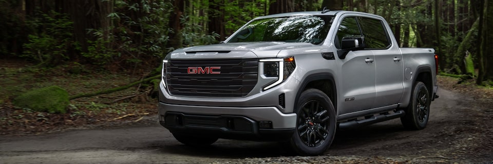 Quicksilver Metallic GMC Sierra Pickup Truck Driving On-Road in Forest