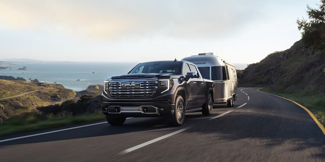 The Pacific Blue Metallic GMC Sierra Denali Towing an Airstreamer on a Beautiful Road