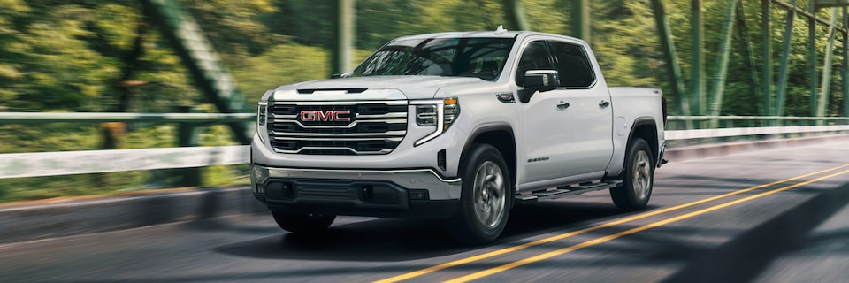 Summit White GMC Sierra SLE/SLT Driving On Bridge With Trees