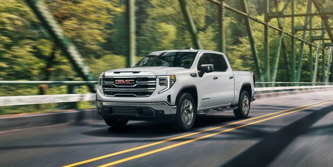 Summit White GMC Sierra SLE/SLT Driving On a Bridge With Trees