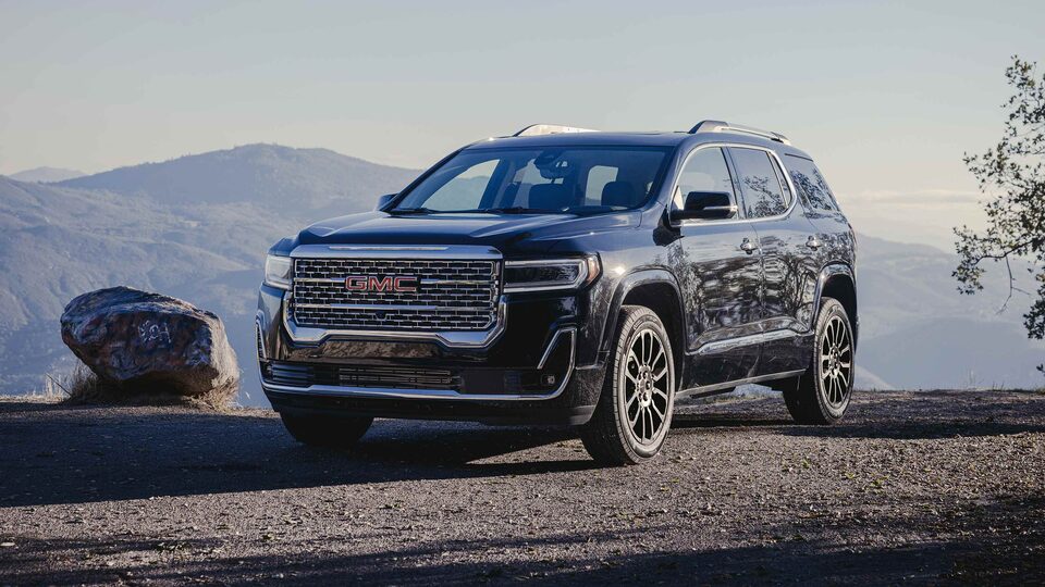 New GMC Acadia Denali Parked Off-Road Next to Boulder and Mountains