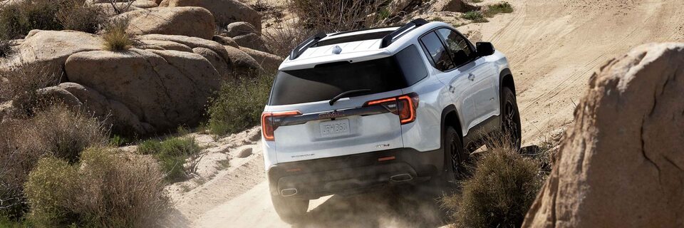 Rear View of the GMC Acadia AT4 Driving Off-Road Kicking Up Dust