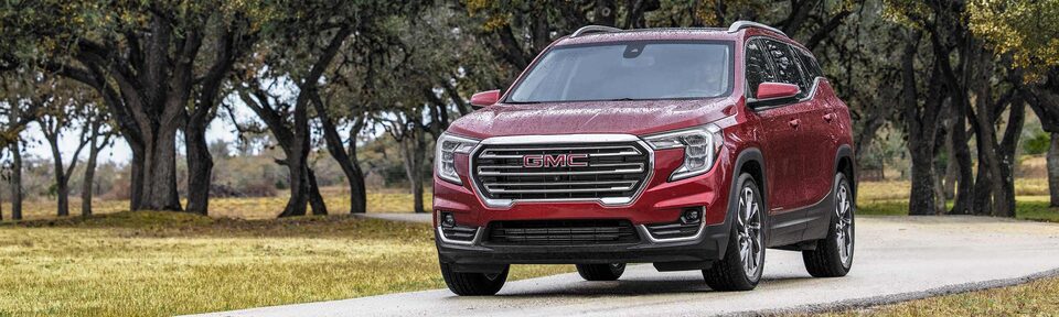 Red GMC Terrain SLT Driving On-Road With Grass and Trees
