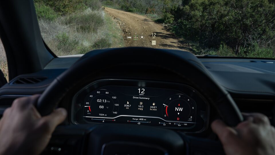 Tech and Safety Features on the Heads-Up Display of the GMC Yukon AT4 Being Driven Off-Road in the Mountains 