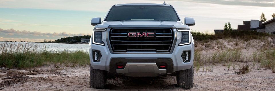 White GMC Yukon AT4 parked on the Beach With Water and Sunset