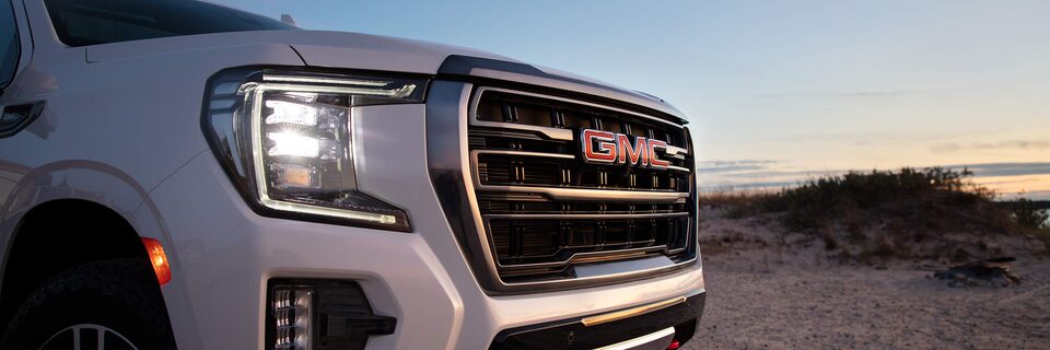White GMC Yukon AT4 Off-Road Parked on a Beach with sunset and water