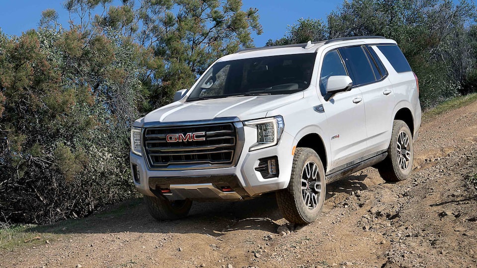 The Summit White GMC Yukon Driving Down-Hill Off-Road On Dirt