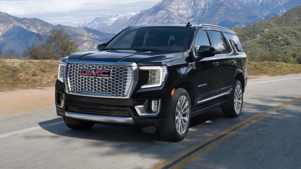 The Onyx Black GMC Yukon Denali Driving On-Road with Trees, Hills, And Mountains