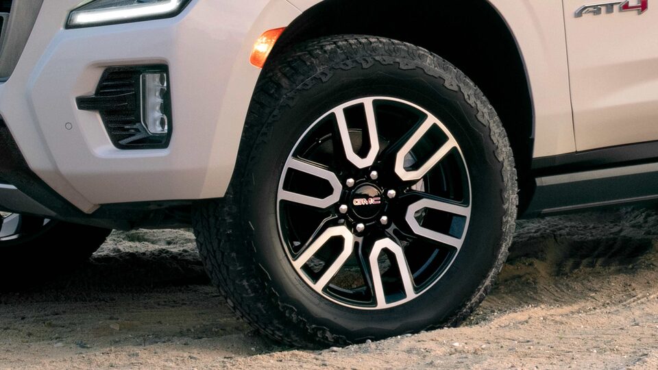 Black Rims and Tires on the White 2023 Yukon AT4 Parked on Sand