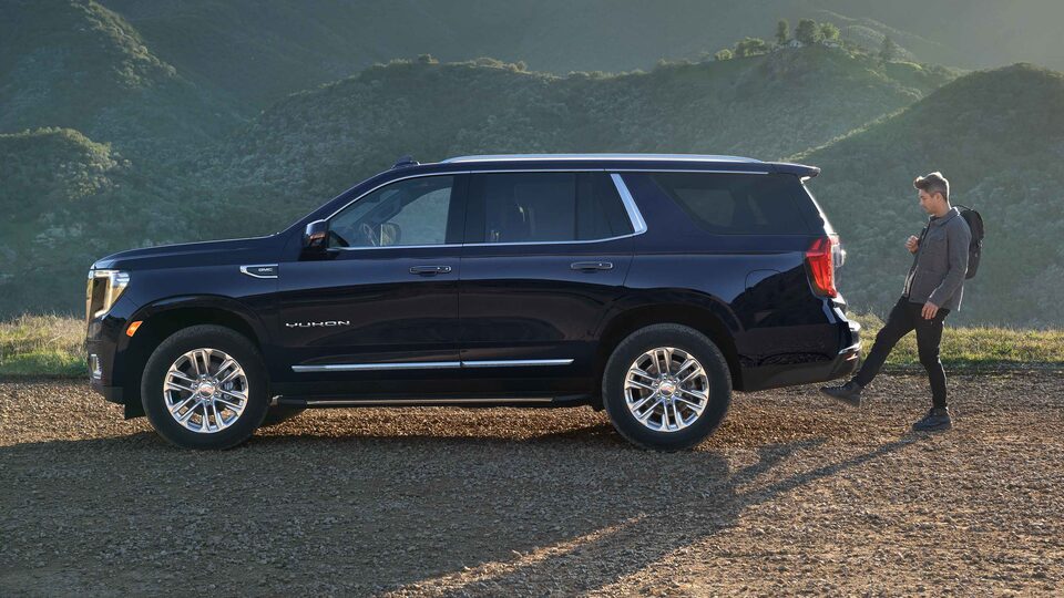 Man Utilizing Hands Free Liftgate on the Parked Dark Blue GMC Yukon with Hills