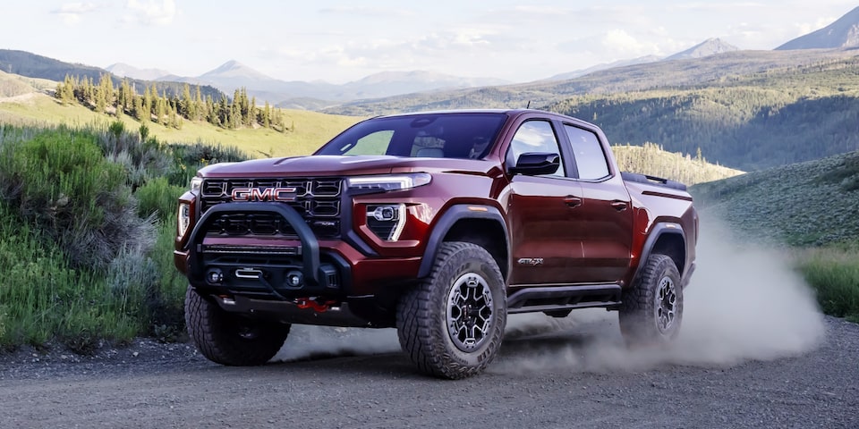 The Canyon At4X Kicking Up Dirt as it Drives Off-Road with a Mountain Backdrop