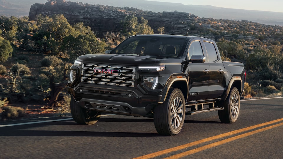 2024 Black GMC Canyon Denali driving down country two way street