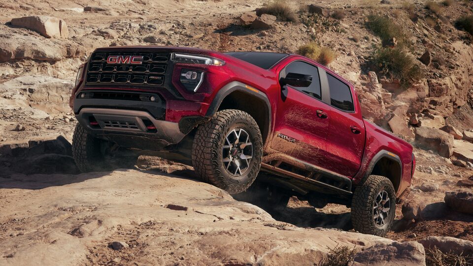 The Red GMC Canyon AT4X Driving Uphill on a Rock in the Desert