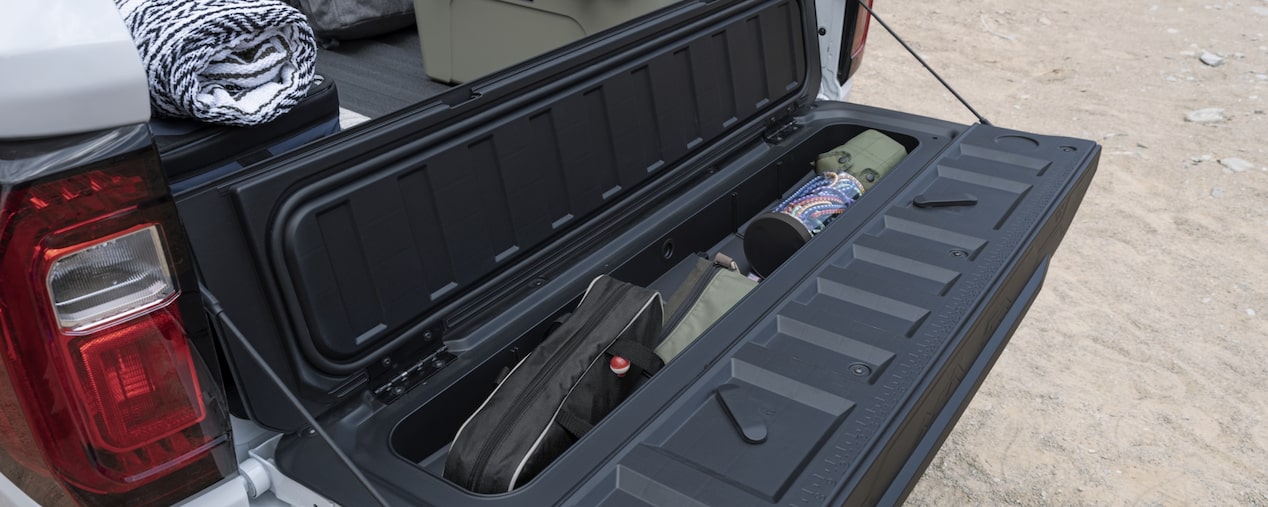 view of the GMC Canyon multistow tailgate storage compartment open full of survival gear