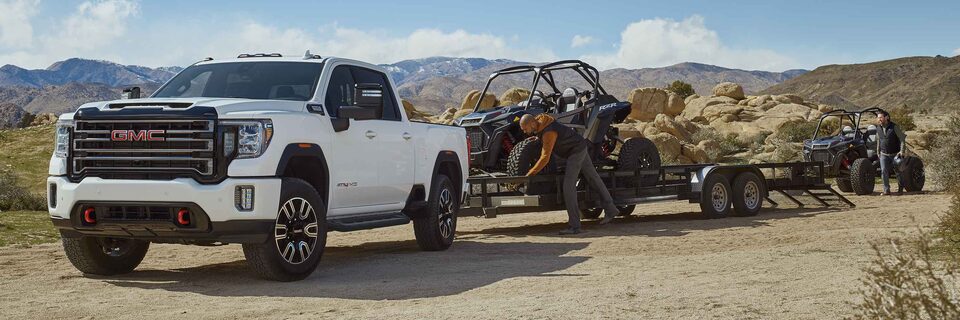 The Powerful GMC Sierra HD AT4 Towing Dune Buggies With Two People Parked