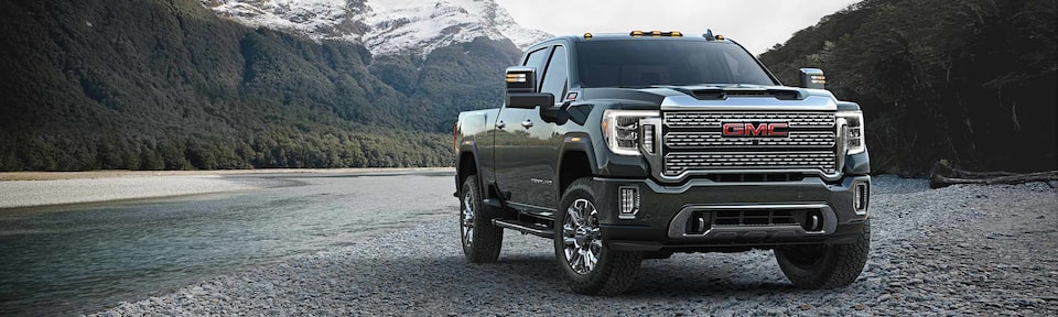 The Stunning Sierra HD Denali Parked Off-Road By a Creek and Mountains