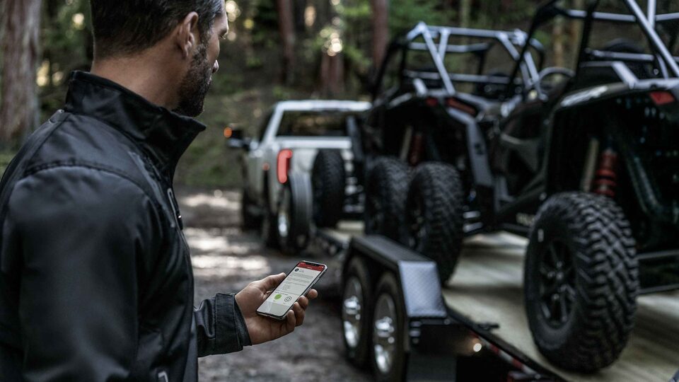 A Main Using His Phone While Standing next to the Sierra LD Towing Dune Buggies