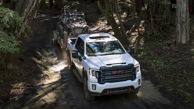 The Powerful Summit White GMC Sierra HD AT4 Driving Off-Road Through Forest