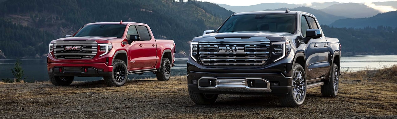 Two 2023 GMC Sierra 1500 trucks in front of a body of water