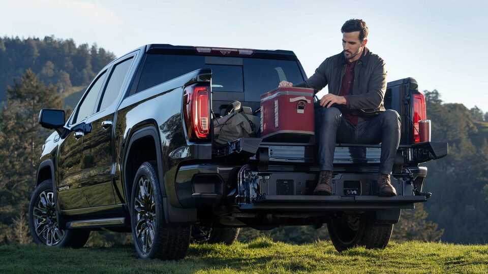 A GMC Sierra Owner Reaches in His Cooler as He Sits in His Truck Bed in the Outdoors