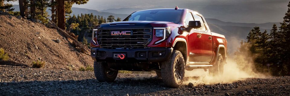 The Sierra 1500 AT4X Kicking Up Dirt as It Climbs an Off-Road Incline
