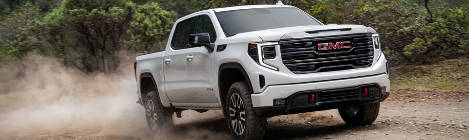 The Sierra 1500 AT4X Kicking Up Dirt as It Climbs an Off-Road Incline