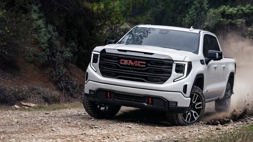 The Summit White GMC Sierra LD AT4 Driving Off-Road on Dirt