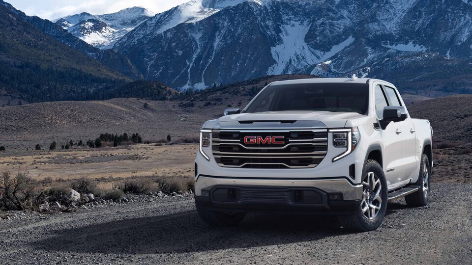 The Sierra 1500 Parked in a Grass Field with a Mountain Backdrop