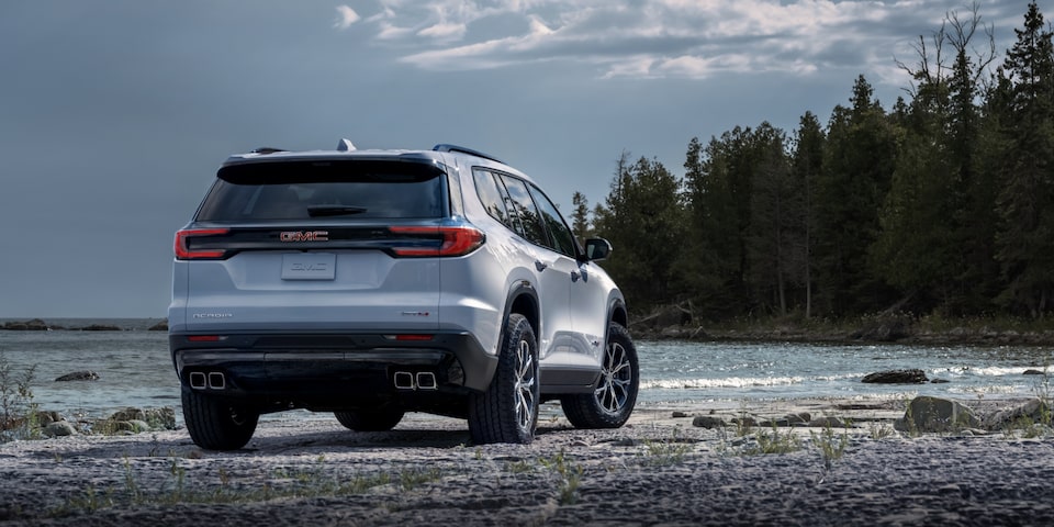 Rear Three-Quarters View of a 2024 GMC Acadia AT4 Surrounded by Trees