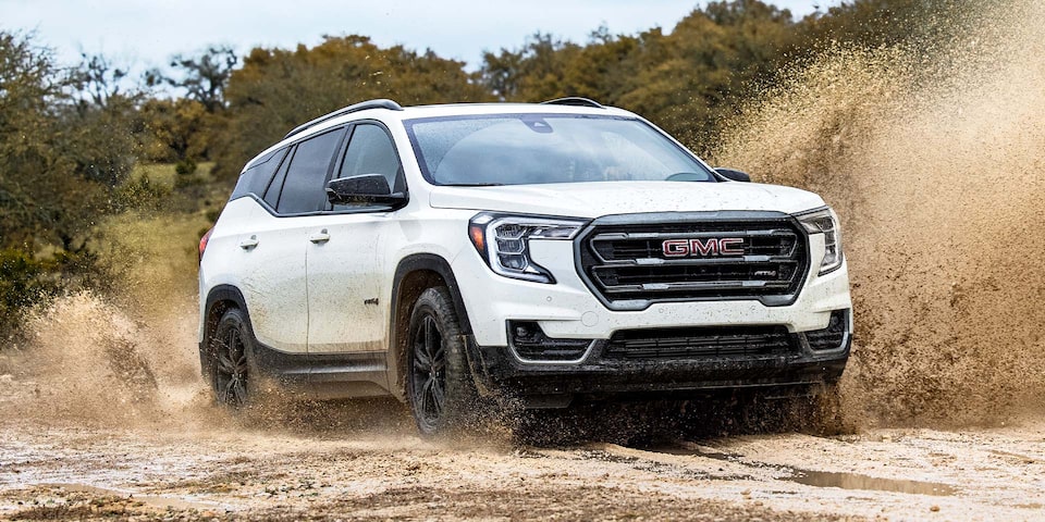 The White GMC Terrain with Gloss-Black Aluminum Wheels Driving Through the Mud