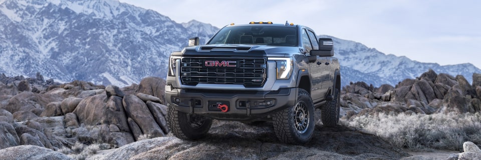 The Tough Looking Sierra HD AT4 Parked on a Mountain Edge with the Red Tow Hook Basking in the Light
