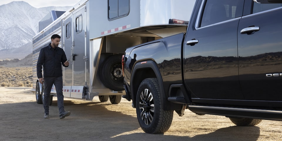 A Man Unlocking His Camper While it is Hooked to the Sierra HD Denali