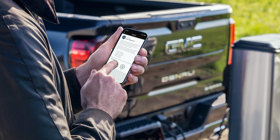 A Person Using the MyGMC App While Standing Next to a GMC Sierra LD Denali