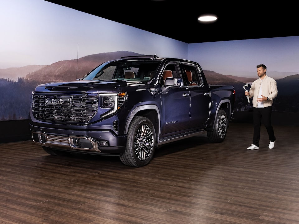 A Showman Standing Next to a GMC Sierra LD During a GMC Live Presentation