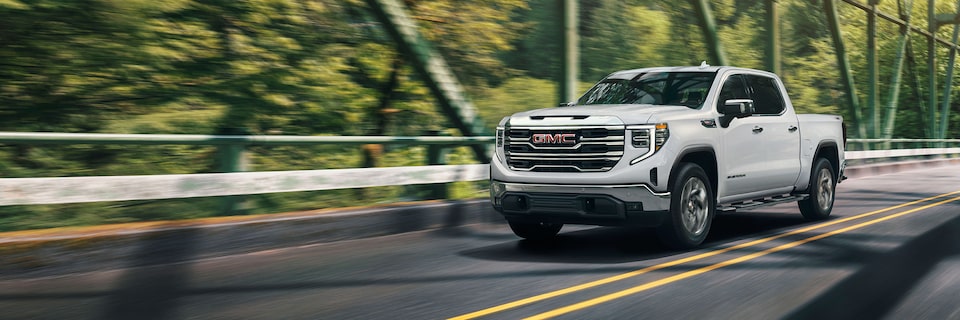 White 2024 GMC Sierra 1500 SLE Driving On-Road Over a Bridge