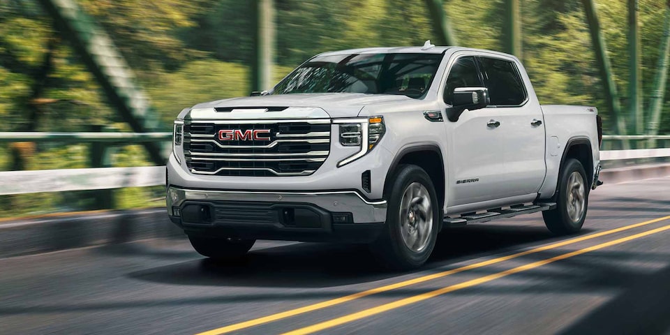 The GMC Sierra LD SLE in Summit White Driving On-Road over a Bridge