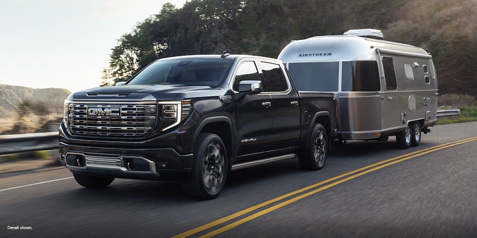 A GMC Sierra LD SLE Driving On-Road Towing a Trailer