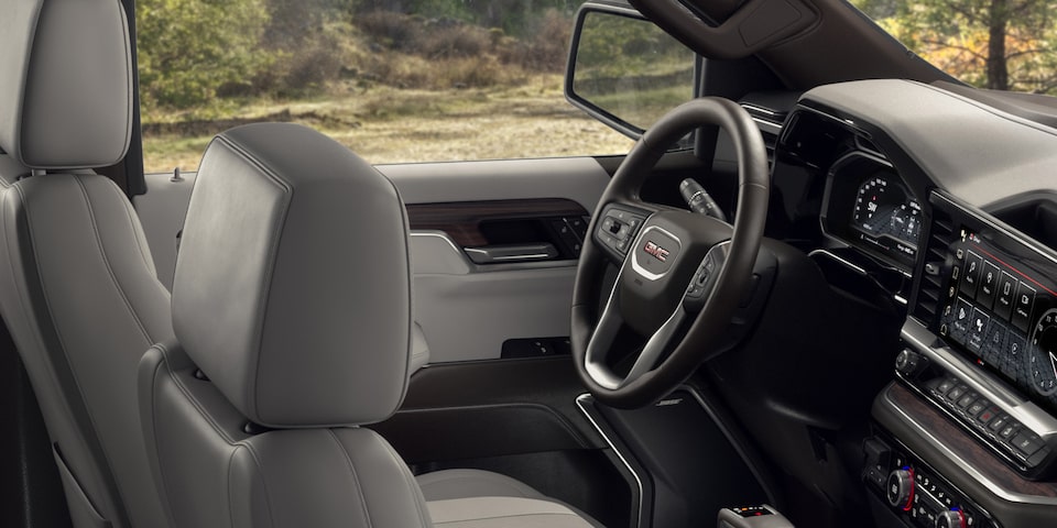 Side Interior View of the Front Seats Head Rest and Steering Wheel of the 2024 GMC Sierra 1500 SLE