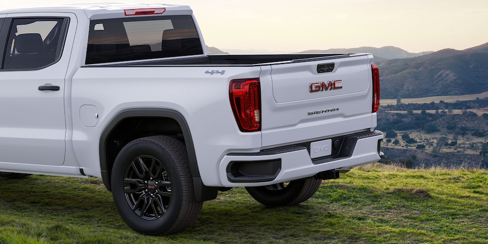 Side Rear View of a White 2024 GMC Sierra 1500 SLE Parked on Grass