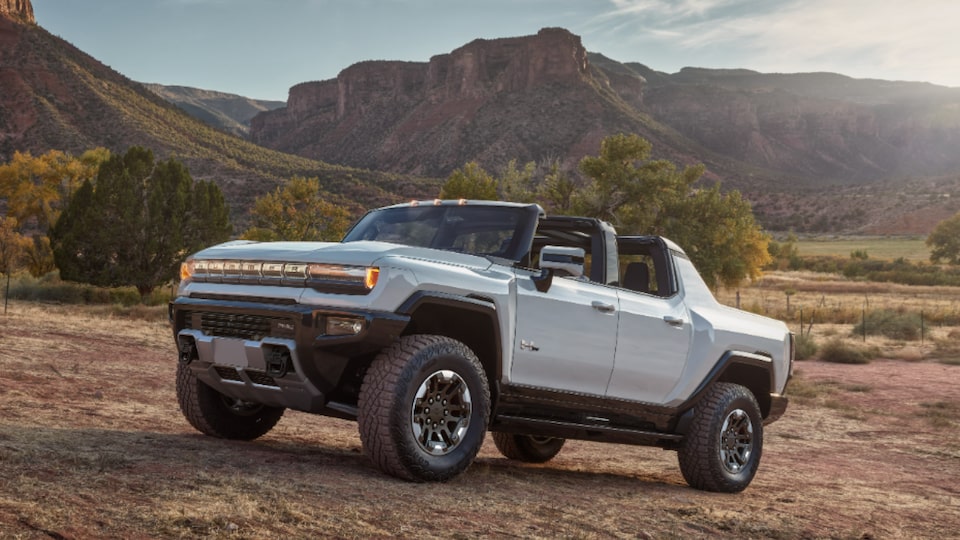 Front Three-Quarters View of a 2025 Hummer EV Pickup Truck Parked Uphill Overlooking Mountains