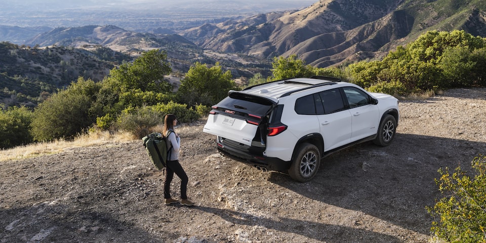 The GMC Acadia AT4 Mid-Size Off-Road SUV Parked on a Mountain While the Driver Opens the Tailgate