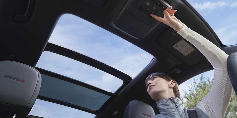 Interior View of the Driver Opening the Panoramic Sunroof in the GMC Acadia
