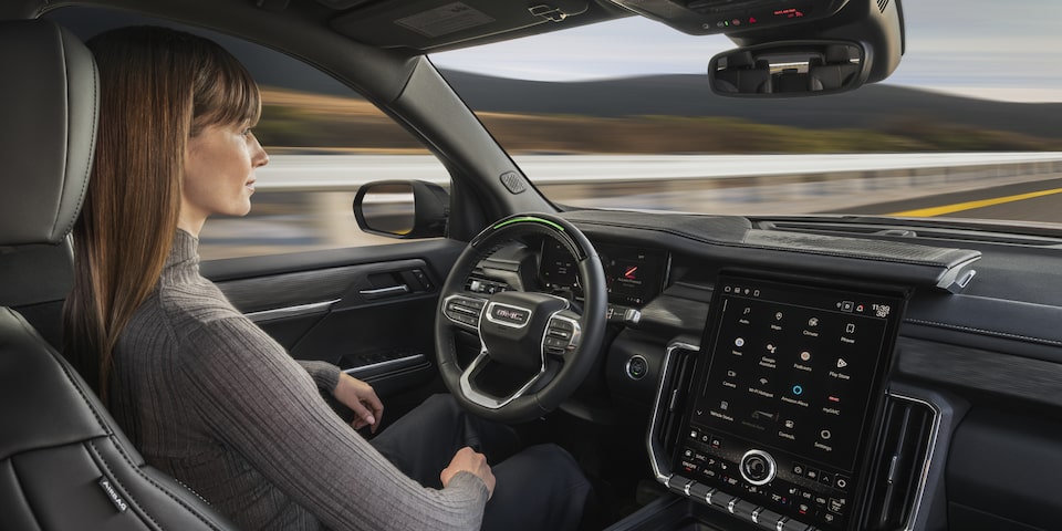 A Woman Sitting in the Drivers Seat of the GMC Acadia SUV Using Super Cruise Hands-Free Driving Technology