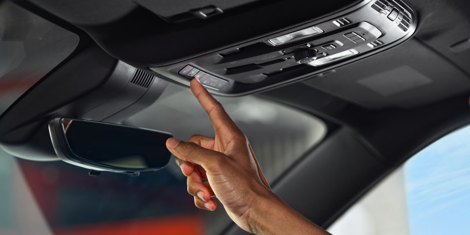A Man Pressing the Blue OnStar Button in his GMC Acadia SUV