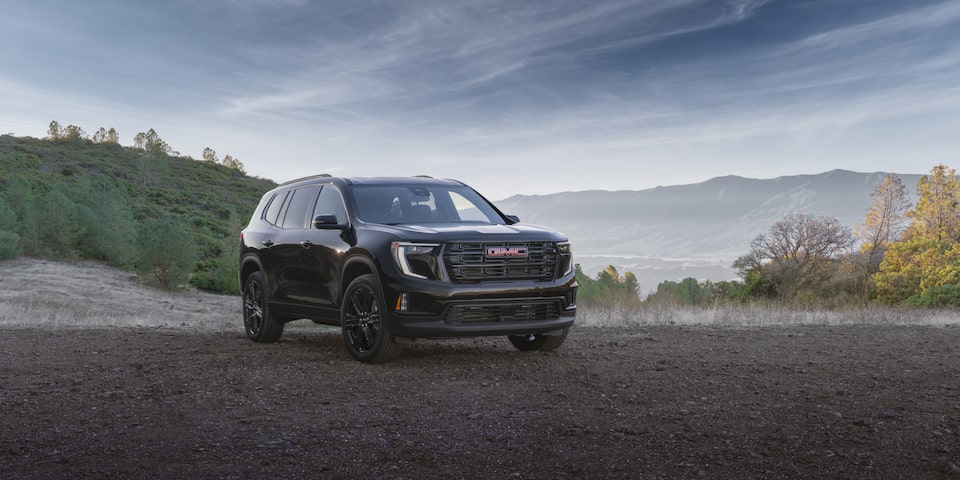 The 2025 GMC Acadia Mid-Size SUV Parked in a Valley with Mountains in the Background
